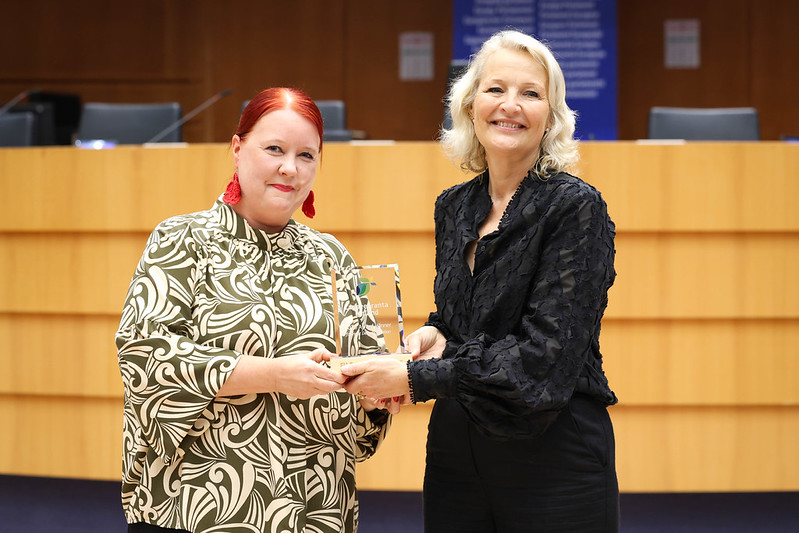 Two people smiling with a prize in their hand.